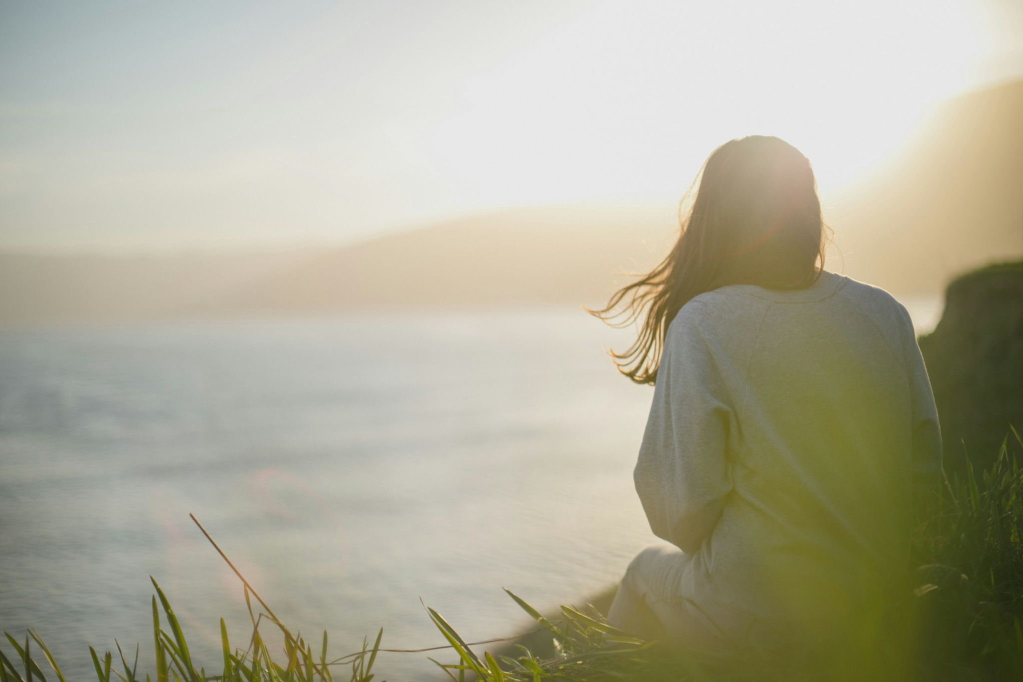 Woman sitting peacefully by the water at sunset